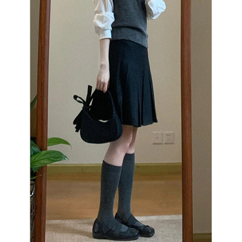 Trojdielny kostým: pletený vest, vrstvená košeľa a vysokopásová A-linijová plisovaná sukňa; jednofarebný vzor, stredná dĺžka sukne, retro štýl