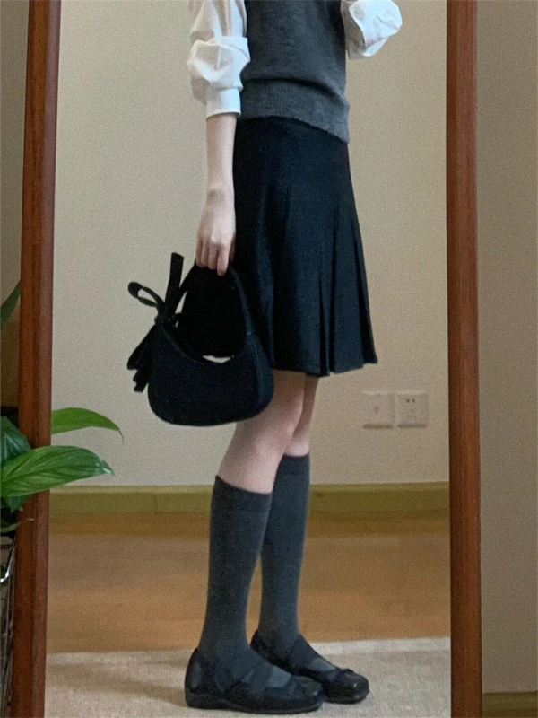 Trojdielny kostým: pletený vest, vrstvená košeľa a vysokopásová A-linijová plisovaná sukňa; jednofarebný vzor, stredná dĺžka sukne, retro štýl