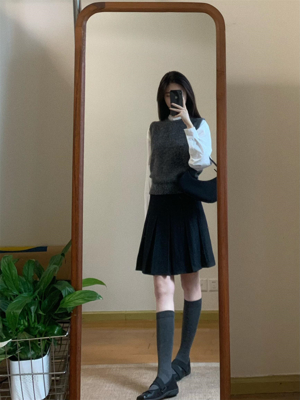 Trojdielny kostým: pletený vest, vrstvená košeľa a vysokopásová A-linijová plisovaná sukňa; jednofarebný vzor, stredná dĺžka sukne, retro štýl