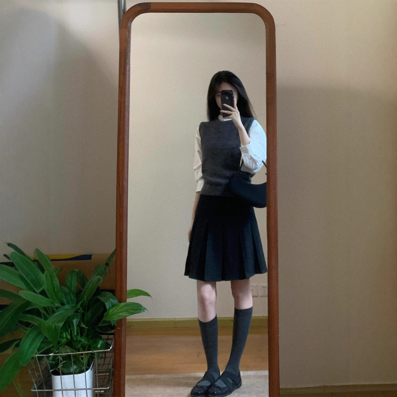 Trojdielny kostým: pletený vest, vrstvená košeľa a vysokopásová A-linijová plisovaná sukňa; jednofarebný vzor, stredná dĺžka sukne, retro štýl