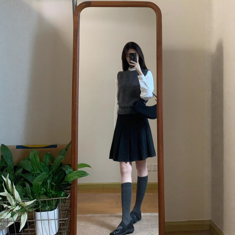 Trojdielny kostým: pletený vest, vrstvená košeľa a vysokopásová A-linijová plisovaná sukňa; jednofarebný vzor, stredná dĺžka sukne, retro štýl