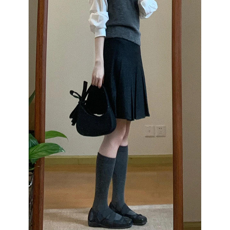 Trojdielny kostým: pletený vest, vrstvená košeľa a vysokopásová A-linijová plisovaná sukňa; jednofarebný vzor, stredná dĺžka sukne, retro štýl