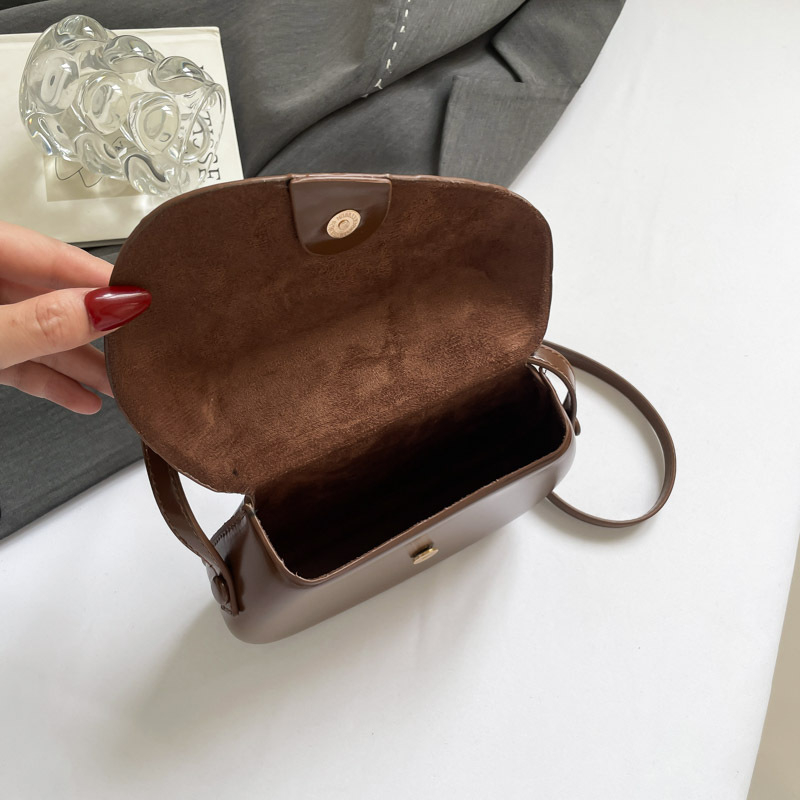 Crossbody soma ar asimetrisku pārklājuma vāciņu un kvadrātveida formu — PU materiāls, poliesteru oderējums, aizvērums ar pārklājošu vāciņu, iekšējie nodalījumi telefoniem un ID, viena pleca siksna