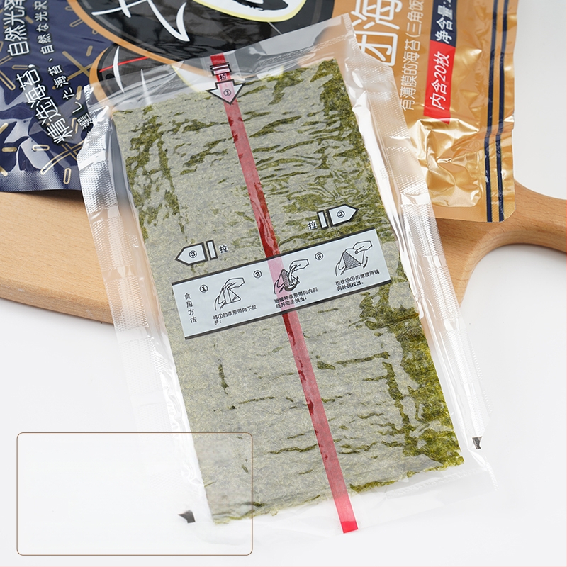 Dvisluoksnis trikampis ryžių kamuoliukų pakavimo maišelis, pusiau supjaustyti jūros dumbliai, rankomis susukta suši pakuotė, lengvai plyštanti ir nerasojanti, japoniško stiliaus jūros dumbliais apvyniota akmens masė