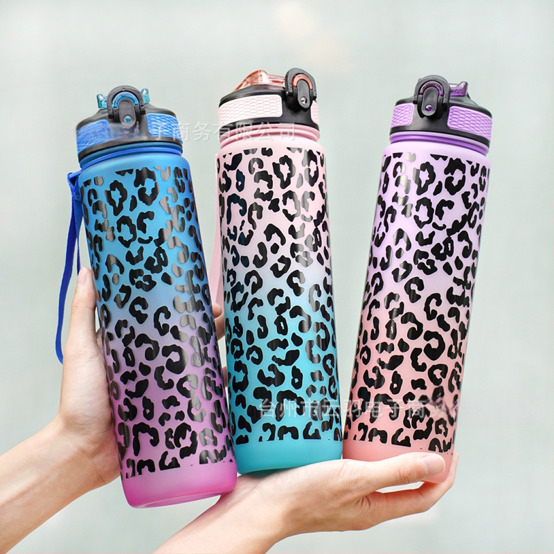 Sandėlyje yra kryžminis gradiento leopardo rašto sportinis plastikinis vandens puodelis su siurbimo vamzdeliu. Leopardo rašto sportinis vandens puodelis.