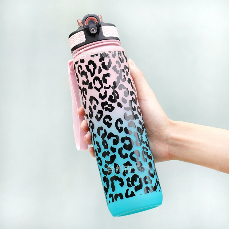 Sandėlyje yra kryžminis gradiento leopardo rašto sportinis plastikinis vandens puodelis su siurbimo vamzdeliu. Leopardo rašto sportinis vandens puodelis.