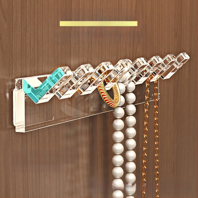 Veidrodinės spintelės durelių gale pakabinama grandinėlės laikymo lentynėlė, rankų grandinėlė, auskarai, sujungti eiliniai kabliukai, apsaugantys nuo susivėlimo, prie sienos tvirtinamas papuošalų stovas be gręžimo