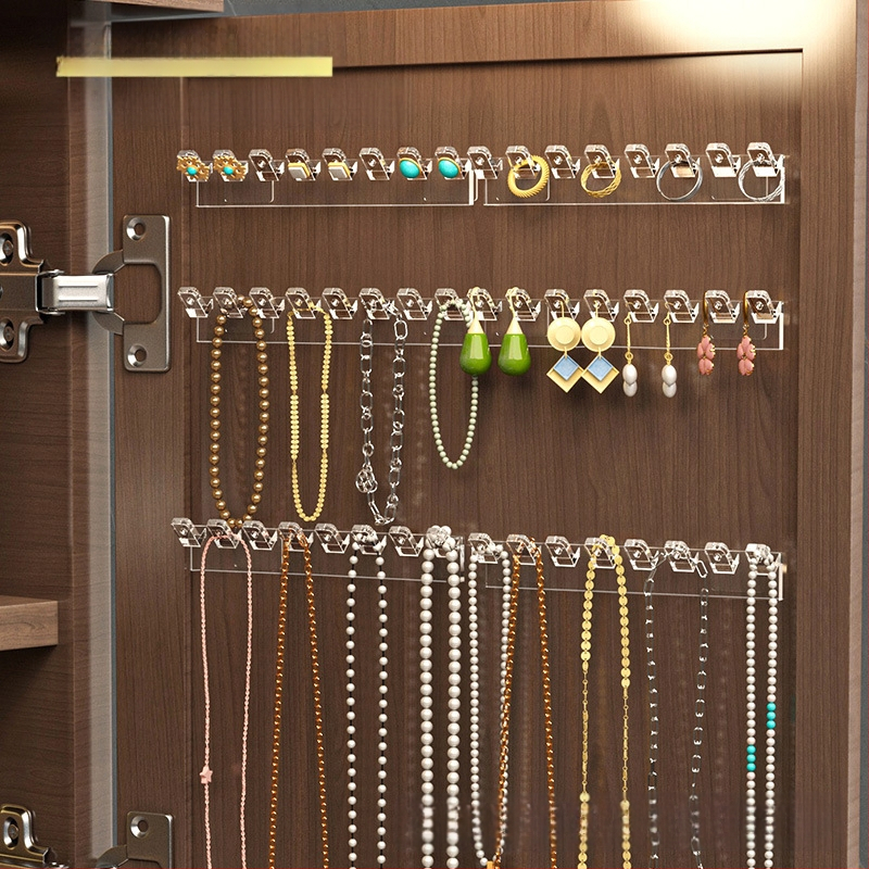 Veidrodinės spintelės durelių gale pakabinama grandinėlės laikymo lentynėlė, rankų grandinėlė, auskarai, sujungti eiliniai kabliukai, apsaugantys nuo susivėlimo, prie sienos tvirtinamas papuošalų stovas be gręžimo