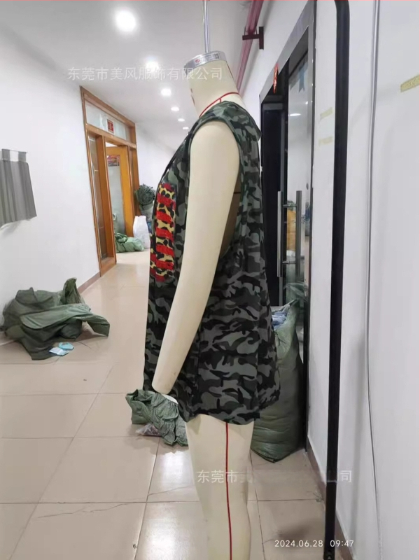 Kamufliažiniai be rankovių marškinėliai su giliu V iškirpte, laisvas kirpimas, audinys – imitacinė medvilnės–poliesterio mišinio (70-80% poliesterio), vasara 2024