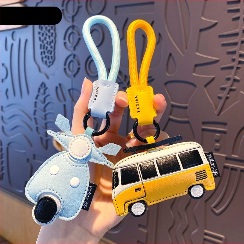 Ādas karikatūru atslēgu piekariņš ar transportlīdzekļu motīviem – automašīna, lidmašīna un autobuss