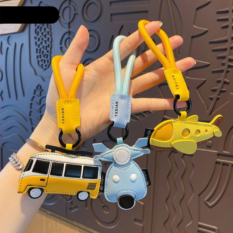 Ādas karikatūru atslēgu piekariņš ar transportlīdzekļu motīviem – automašīna, lidmašīna un autobuss